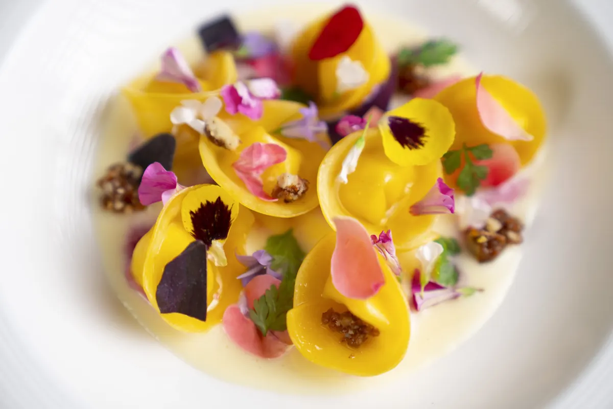 Ravioli ai frutti selvatici, miele e curry, formaggio d'alpe e fiori